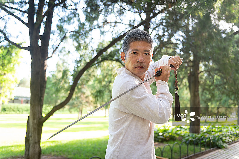 中国男子在公园里练太极直剑。图片素材