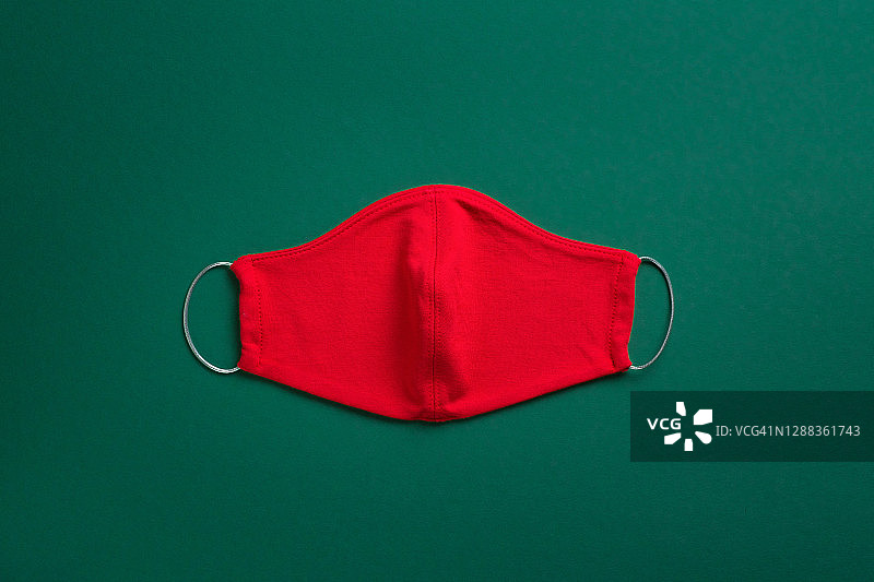 红色医用口罩，绿色圣诞背景。预防和预防covid-19大流行的传播。预防病毒、感染和肺炎。一个快乐健康的圣诞节概念。图片素材