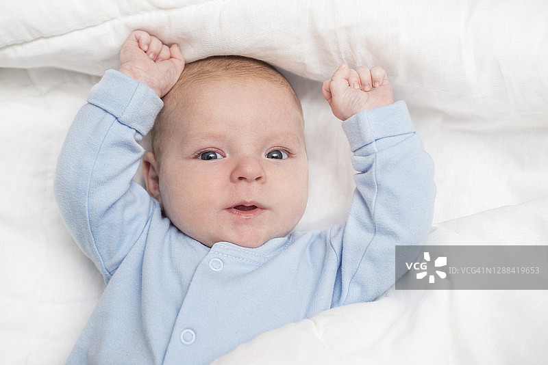 一个可爱的婴儿躺在床上的肖像。婴儿躺在白布上图片素材