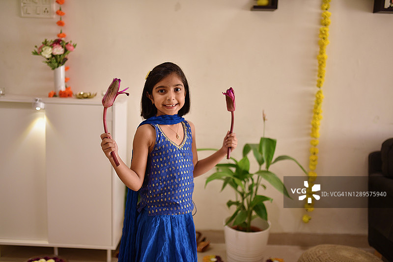 一个穿着印度传统服装的可爱女孩的肖像，手里拿着莲花图片素材