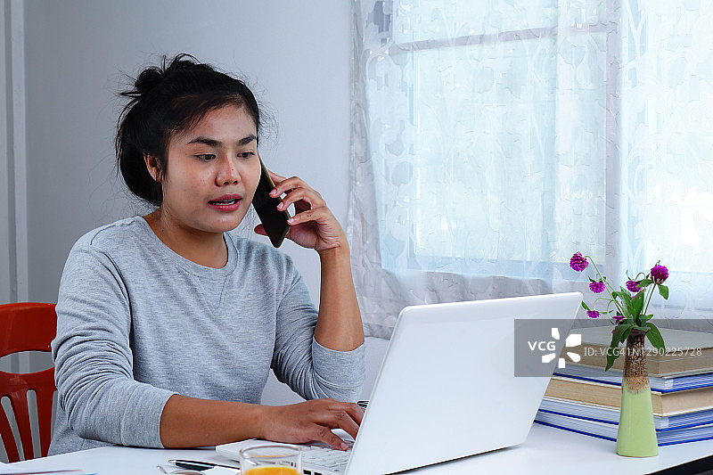 亚洲女性在家工作。在家工作变得正常。图片素材