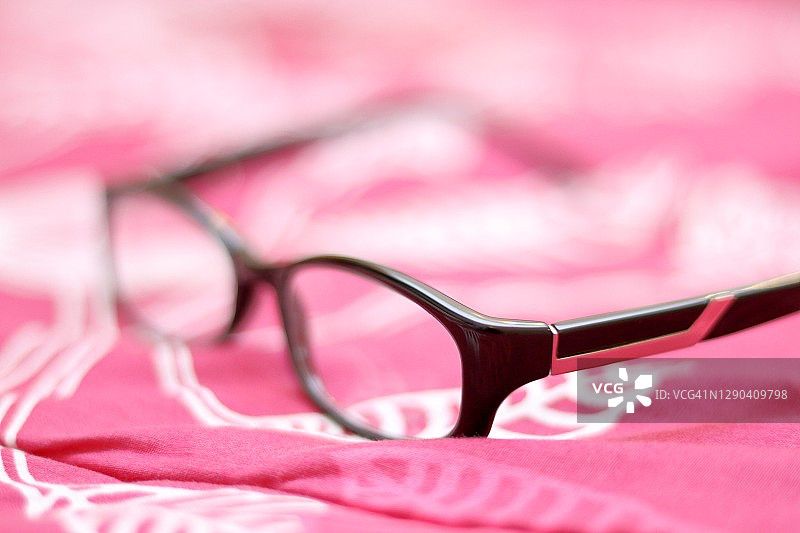 在粉红色设计背景下的眼镜。图片素材