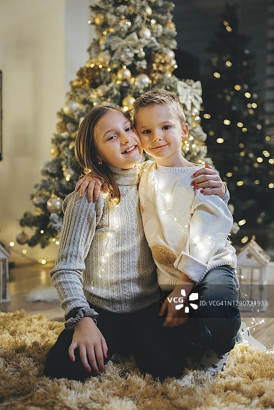 哥哥和妹妹在圣诞树前互相拥抱图片素材