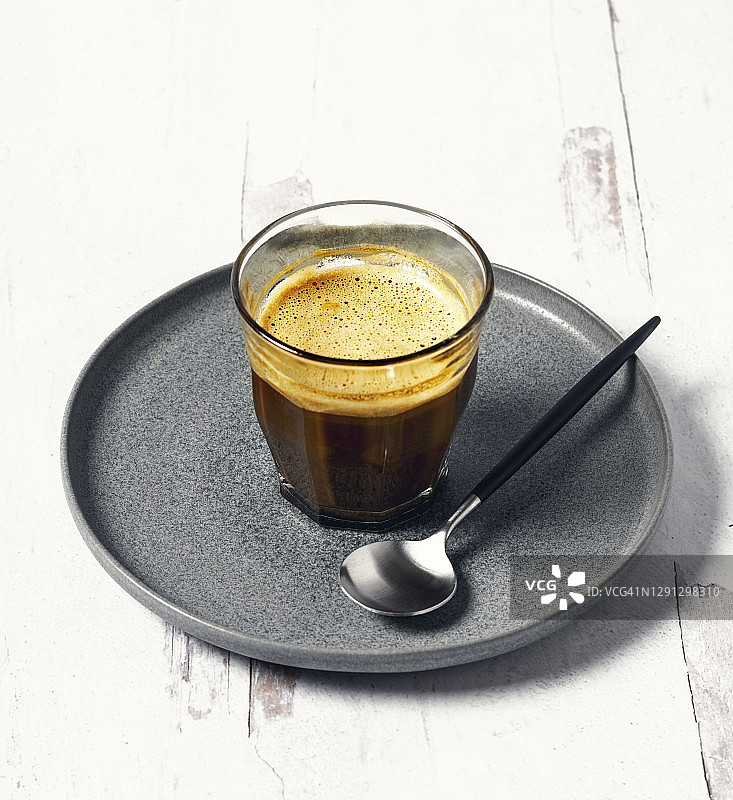 一勺浓咖啡，放在灰色的盘子里，背景是白色的图片素材