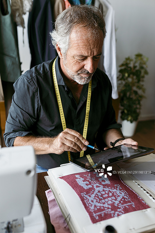 男性服装设计师使用数字平板电脑在工作室工作图片素材