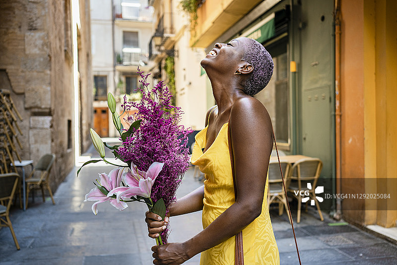 兴高采烈的女人拿着花站在城市的路边咖啡馆图片素材
