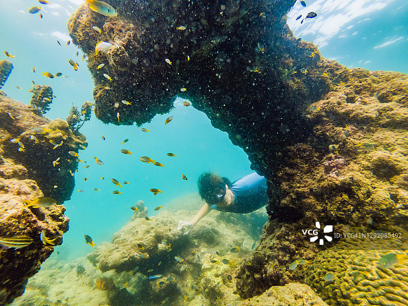年轻人浮潜探索水下珊瑚礁景观背景在深蓝色的海洋与丰富多彩的鱼类和海洋生物图片素材