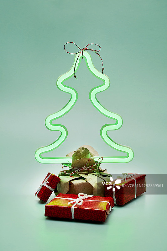 一个小照明圣诞树灯的静物生活和礼物在绿色的背景图片素材