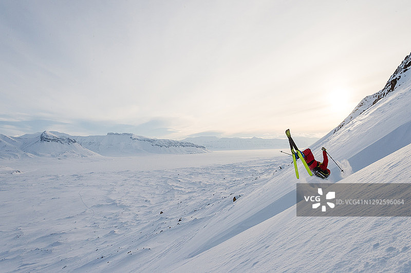 滑雪登山运动员在山谷上方陡峭的山坡上表演特技图片素材