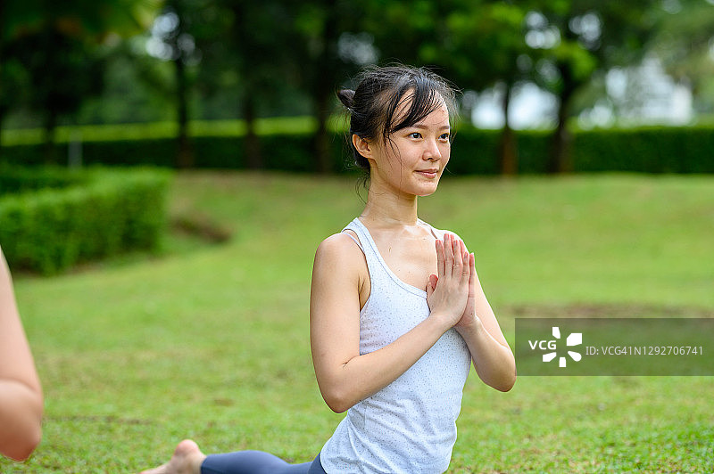年轻的健身亚洲妇女练习瑜伽树姿势在一起放松的自然图片素材