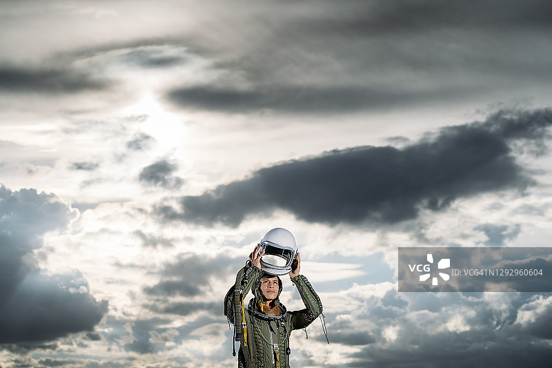 一名男子装扮成宇航员站在草地上，背景是壮观的云彩图片素材