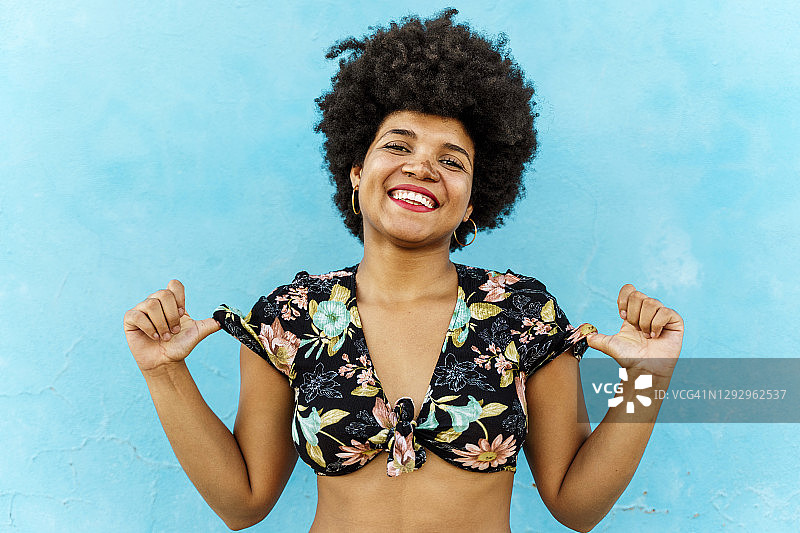 一位在蓝色墙壁前微笑的非裔美国妇女图片素材