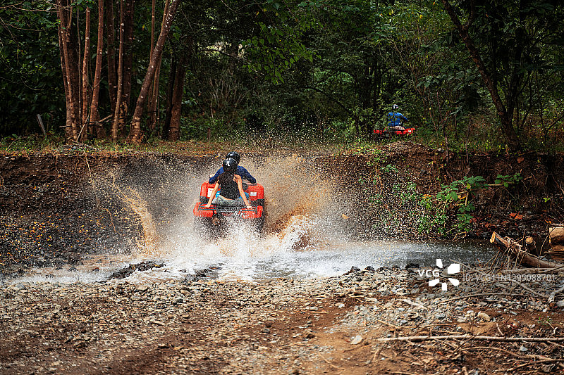 在哥斯达黎加，游客驾驶四轮摩托车穿过一条小溪图片素材