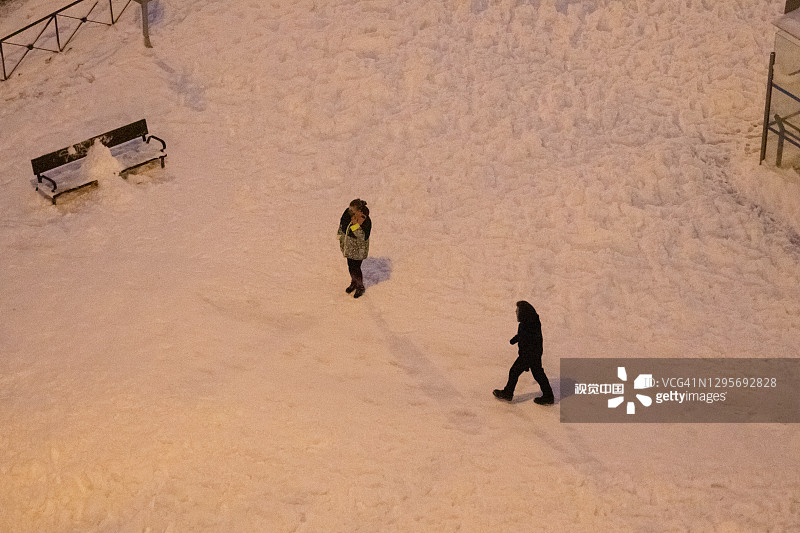 人们在被雪覆盖的道路中间行走和玩耍，因为汽车不能通过由于雪。菲洛梅娜风暴给马德里带来了一场大雪图片素材