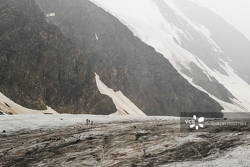 在山脚下的冰川是登山运动员。阿尔泰雪山美丽自然的色调照片。小的人。Aktru冰川。山阿尔泰。西伯利亚。俄罗斯。图片素材