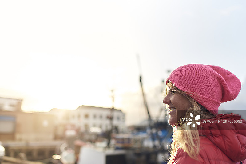 迷人的金发女人在户外服装微笑的镜头，而走在海港图片素材