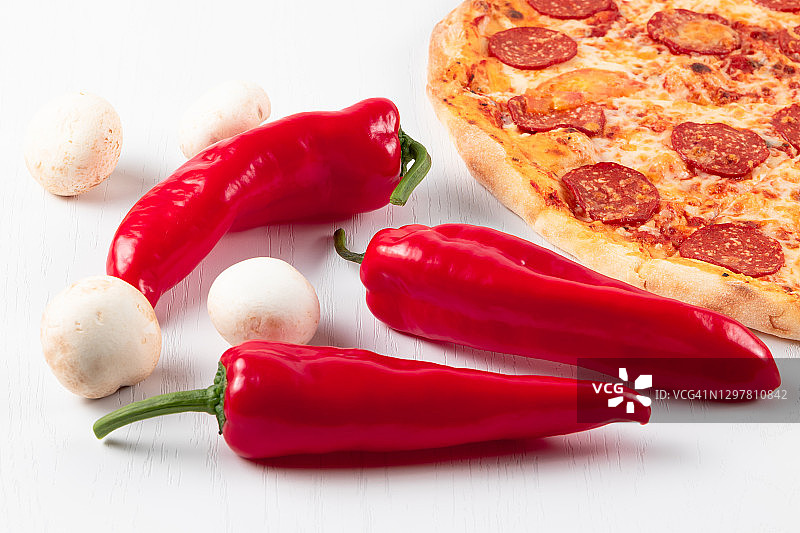 白色木桌背景上放着新鲜的意大利辣香肠披萨，配上马苏里拉奶酪、红辣椒和蘑菇图片素材
