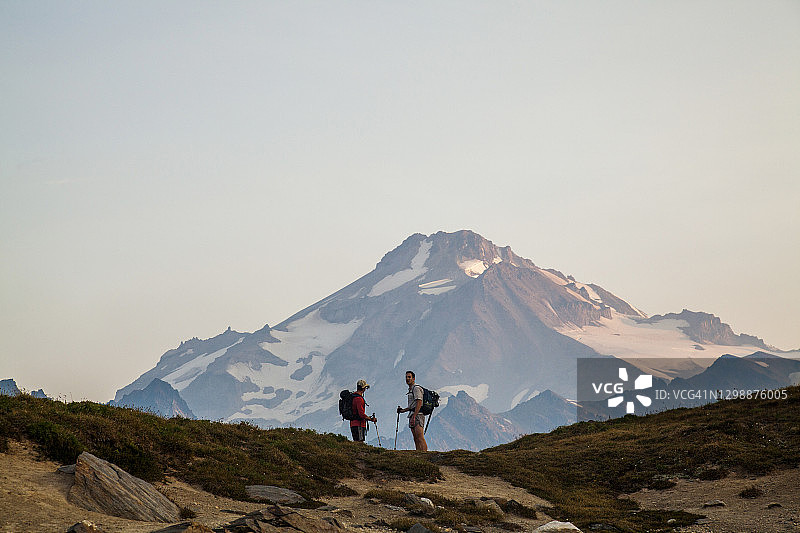 两名徒步旅行者在黎明时向冰川峰攀登。图片素材