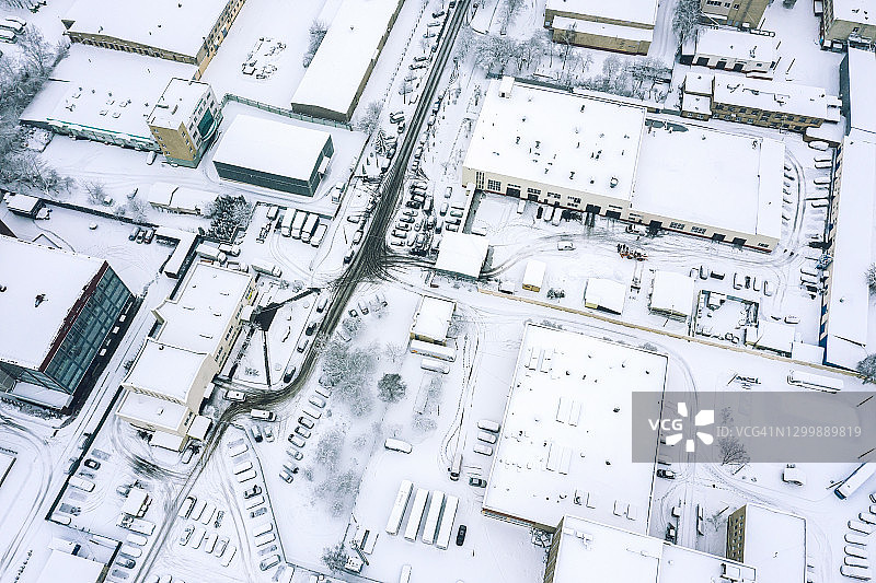 在雾霾弥漫的冬日里，飞过被雪覆盖的城市工业区图片素材