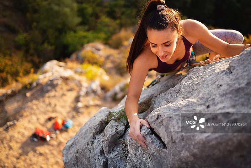 强壮的女性攀登在大自然的岩石山上图片素材