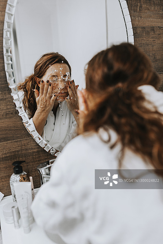一个女人在镜子前洗脸图片素材