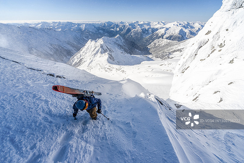 滑雪登山运动员登上山顶斜坡，山下有山图片素材