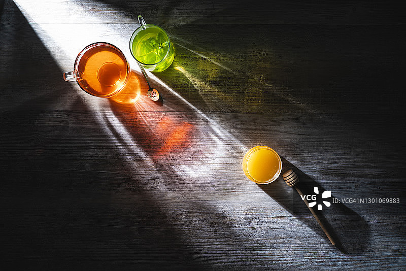 红黑茶杯和薄荷加蜂蜜茶在灰色的木桌和光线图片素材