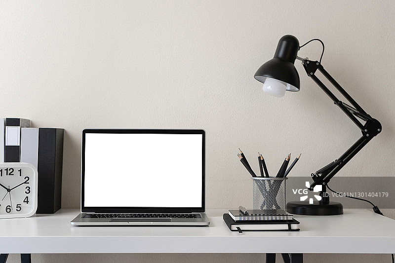 现代现代的工作空间与空白屏幕笔记本电脑办公用品和文具办公桌上的白色背景的复制空间。家庭办公室工作场所的概念。图片素材