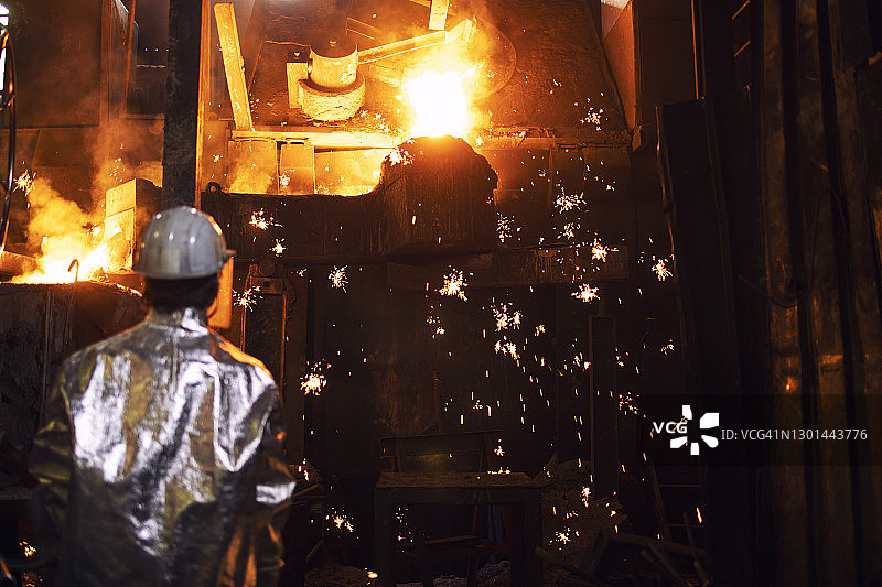 铸造工人控制铁在炉中熔化。火花飞舞。图片素材