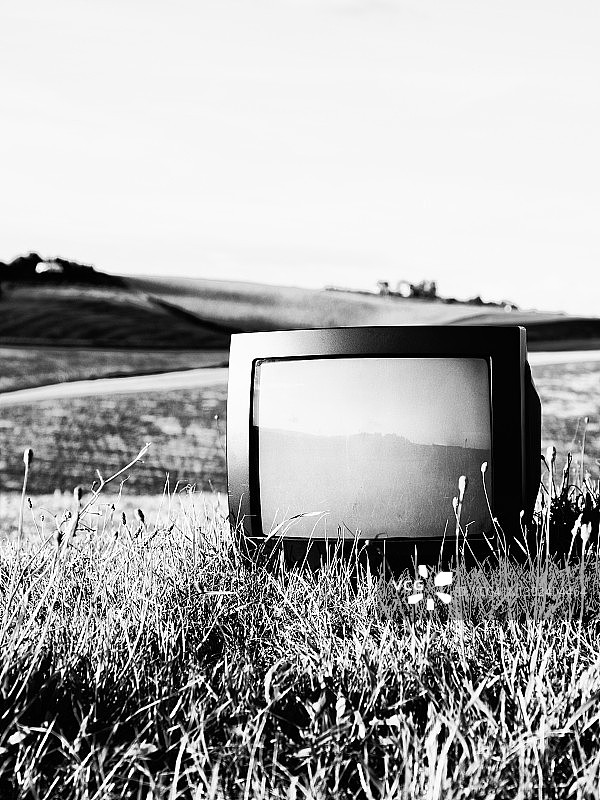 废弃在田里的旧电视。图片素材