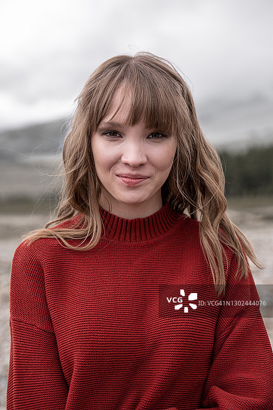 一个年轻女孩的微笑肖像。山阿尔泰自然。旅游行程。穿着红色针织毛衣的漂亮女孩。图片素材