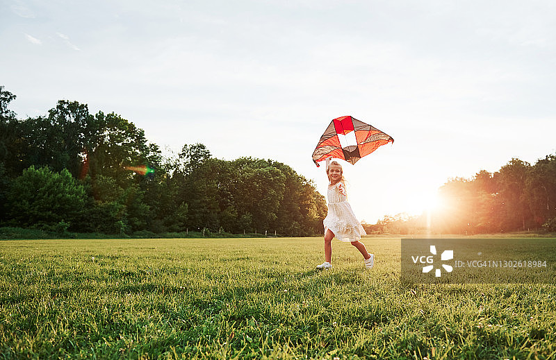 大草原。穿着白色衣服的快乐女孩在田野里玩风筝。美丽的大自然图片素材