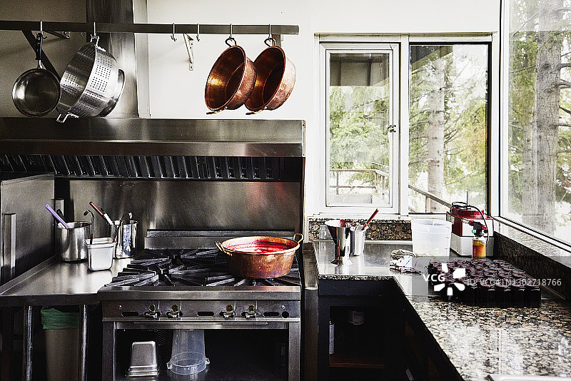 商业厨房的观点与铜锅上的炉子和新鲜制作的有机果酱柜台图片素材