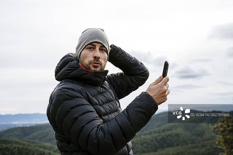 冬季，男性游客手持智能手机观看天空图片素材