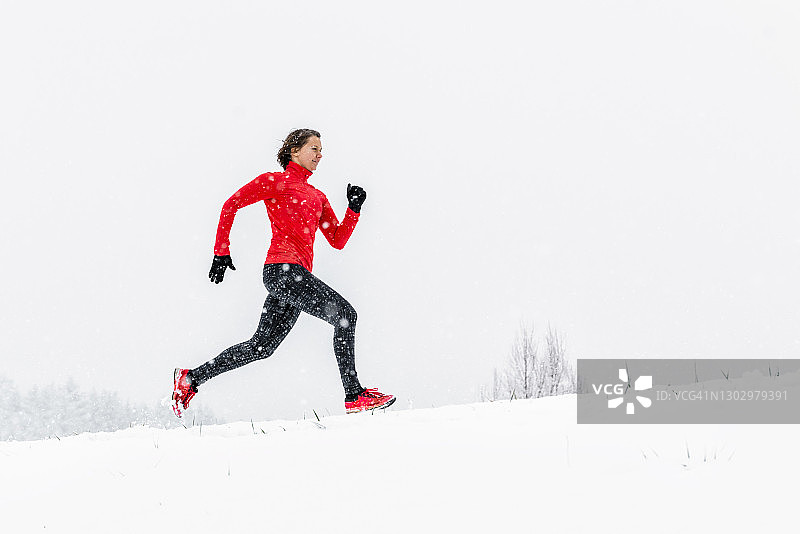年轻女运动员冬天在雪地上跑步图片素材