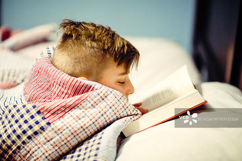 男孩在床上看书图片素材