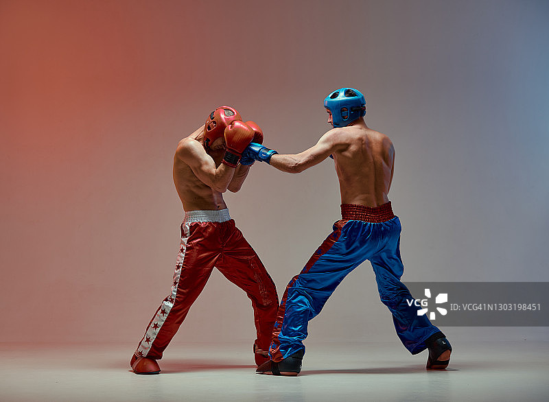运动员对打格斗，拳击手在红色演播室灯光下训练，混合格斗训练图片素材