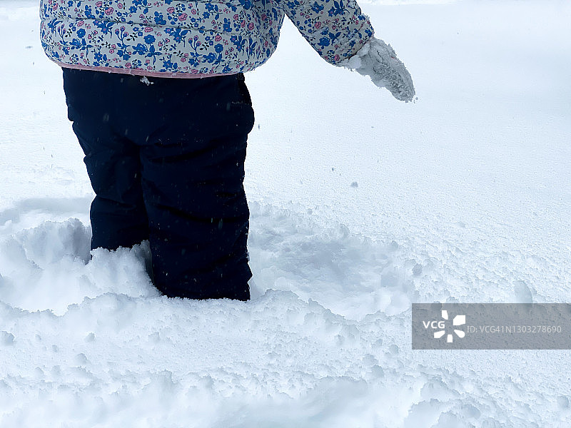 一场冬季暴风雪过后，顽皮的幼儿在试图走在厚厚的雪地里时停顿了一下图片素材