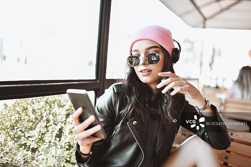 现代女性美女一边喝咖啡一边用智能手机听音乐图片素材