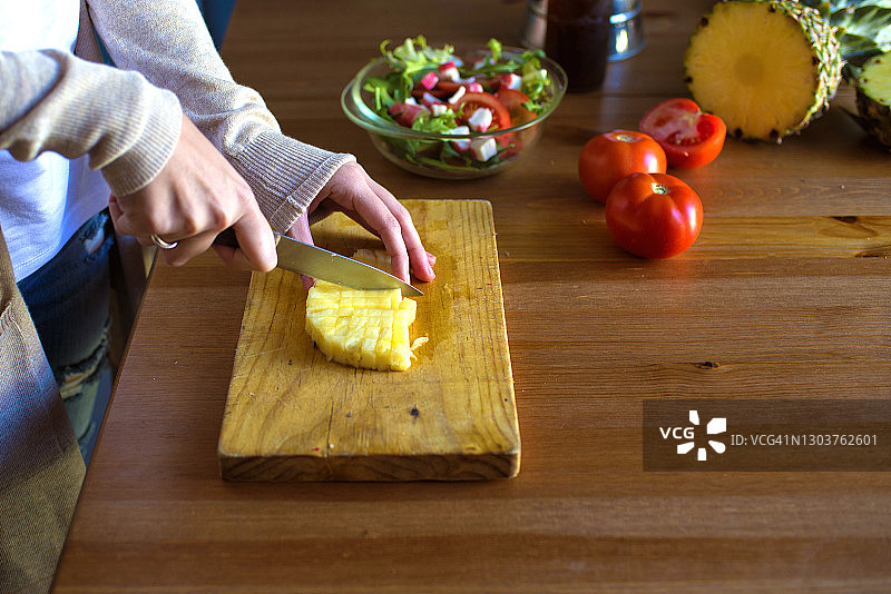一个女人在厨房里切菠萝做沙拉图片素材