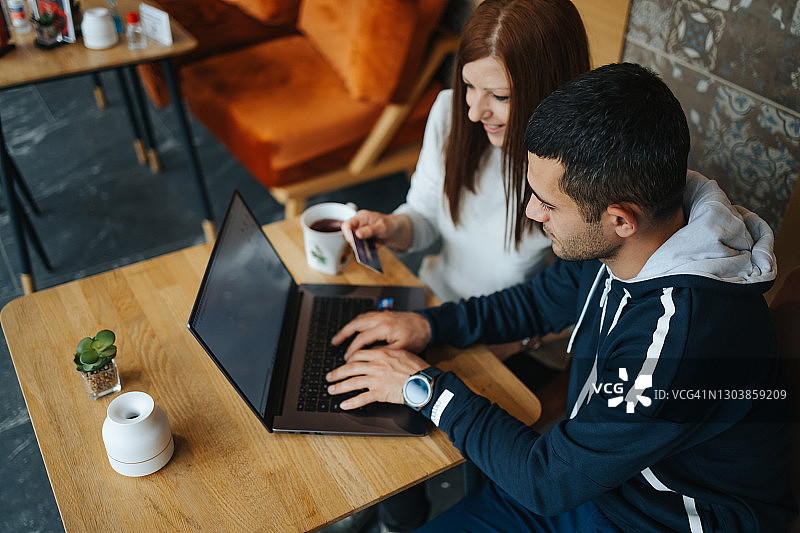年轻夫妇在咖啡馆喝茶和使用笔记本电脑图片素材