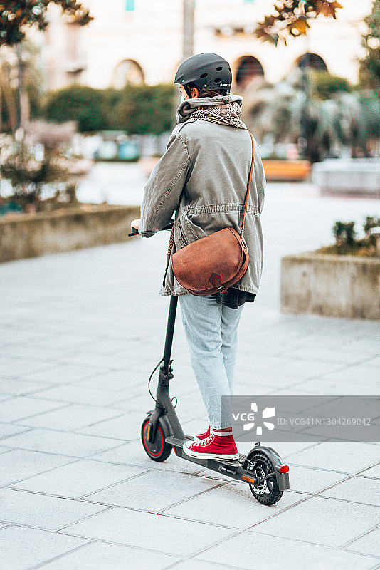 一个女人骑着滑板车的后视图图片素材