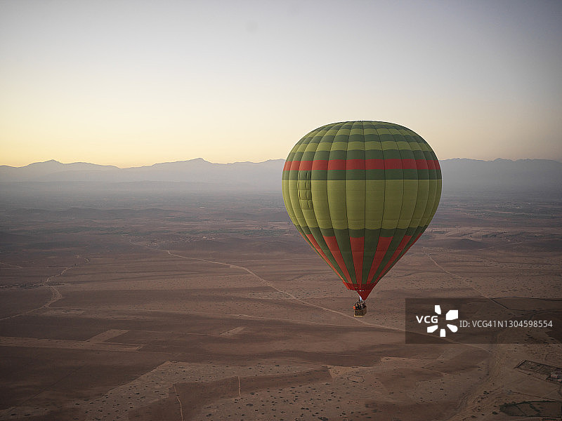 热气球飞过摩洛哥马拉喀什外的沙漠，日出图片素材