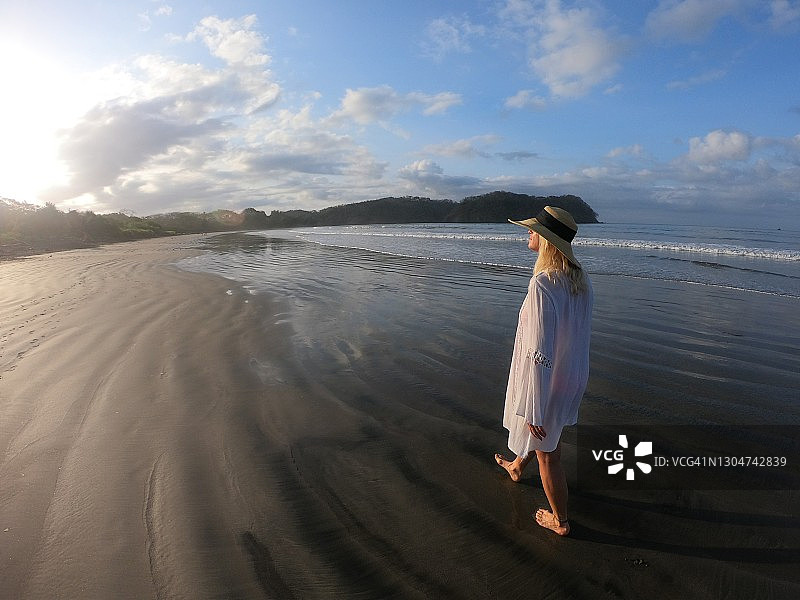 日出时分，一个女人走在沙滩上图片素材