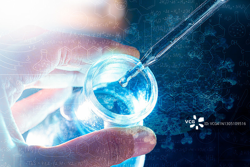 手握烧瓶与实验室玻璃器皿和试管在化学实验室的背景，科学实验室研究和发展的概念图片素材