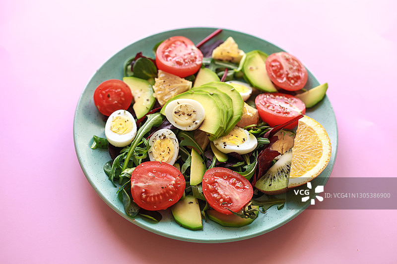 用叉子把生蔬菜和水果做成的新鲜沙拉放在桌上。健康素食有机食品的概念。健康的饮食习惯。图片素材