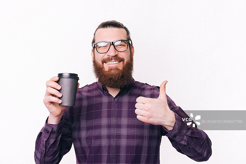 快乐的大胡子男人竖起大拇指，端着咖啡走了图片素材