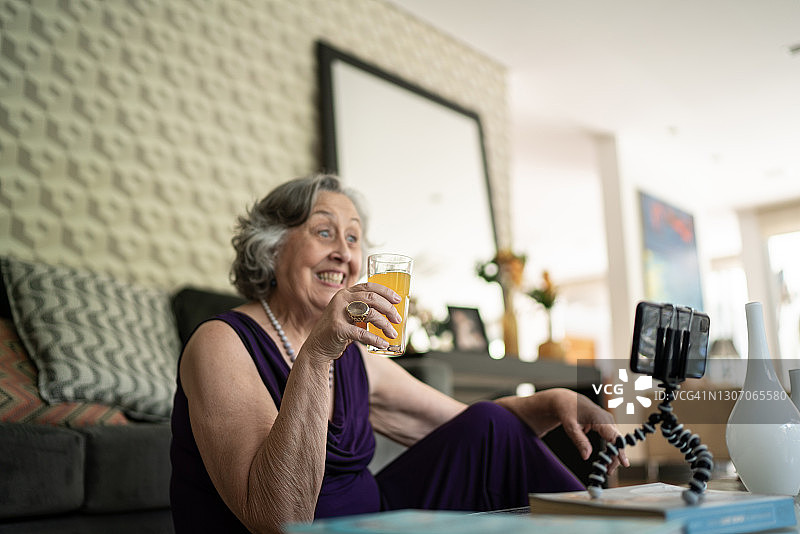 老女人在家用智能手机打视频电话或拍视频图片素材