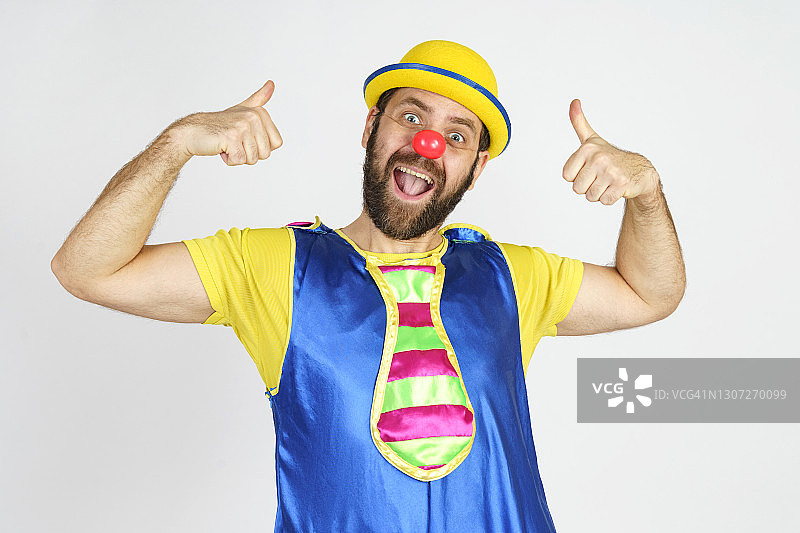 穿着亮蓝色和黄色套装的小丑把手指向上指图片素材