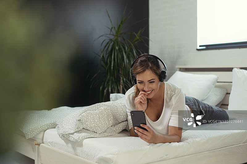 一个穿着睡衣戴着耳机听音乐的年轻女人的肖像图片素材